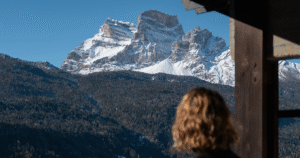 Woman from behind admiring the Dolomites view from the terrace of Hotel Boite in Borca di Cadore