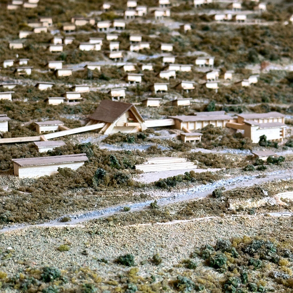 Detail of a scale model of the Eni Village in Borca di Cadore, showing chalets, roads and buildings set within the mountain landscape. An exhibition piece narrating Edoardo Gellner’s urban vision.